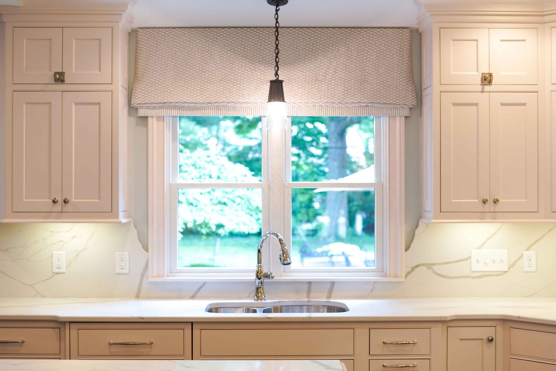 A kitchen with a sink , cabinets , and a window.