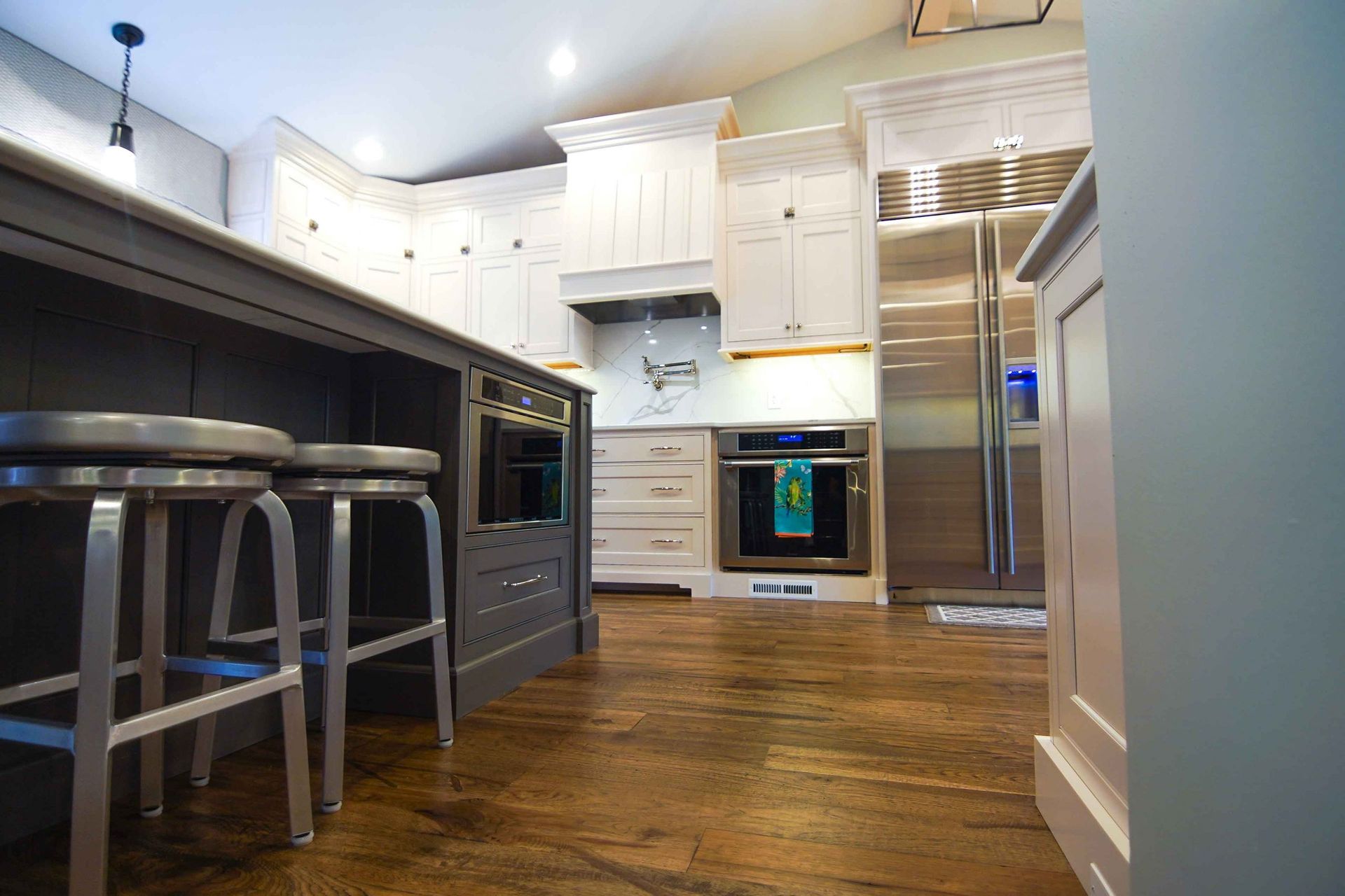 A kitchen with white cabinets , stainless steel appliances and hardwood floors.