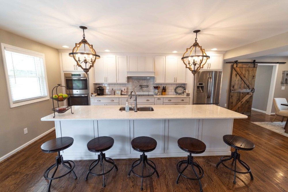 A kitchen with a large island and stools in it.