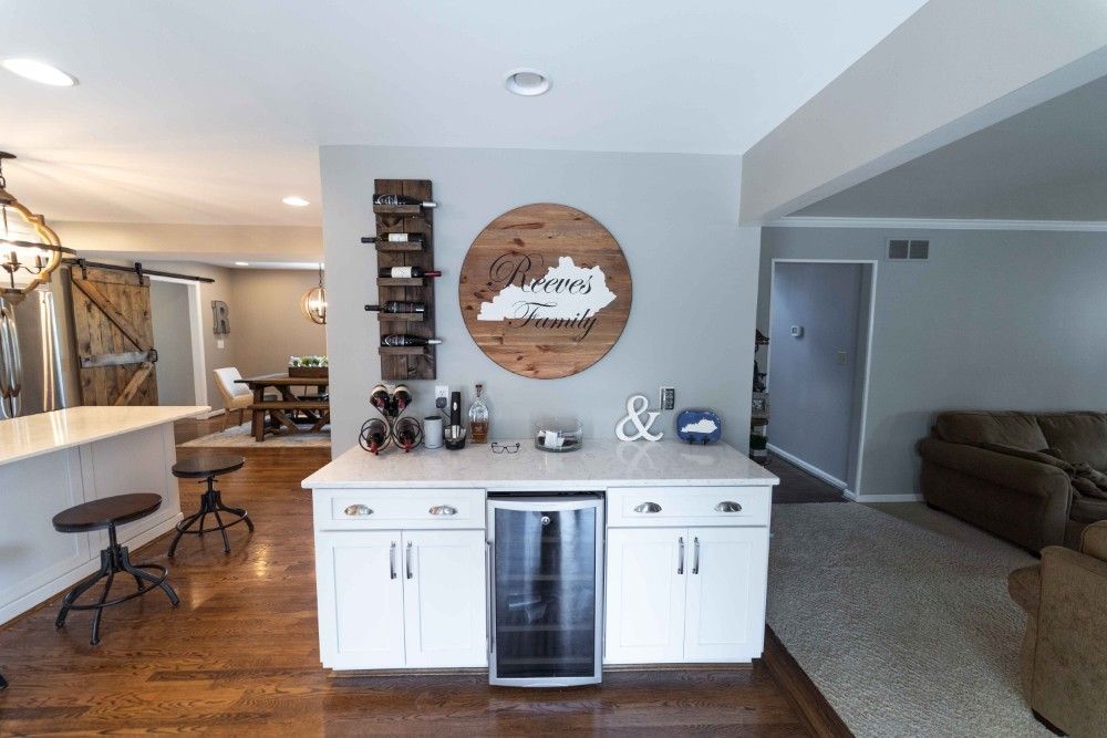 A kitchen with a wine cooler and a wooden sign on the wall.