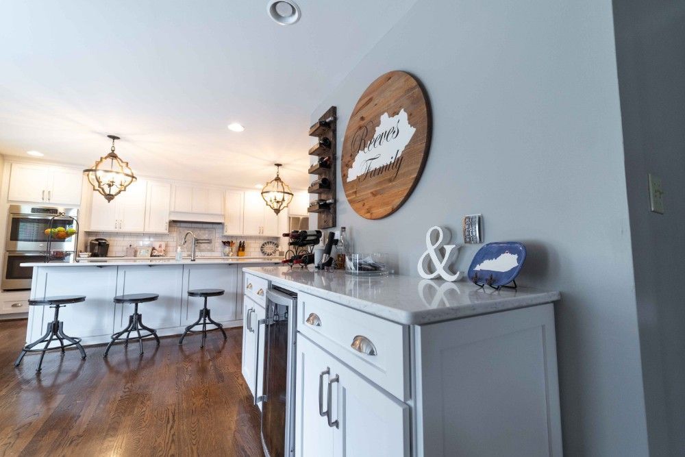 A kitchen with white cabinets and a wooden sign on the wall.