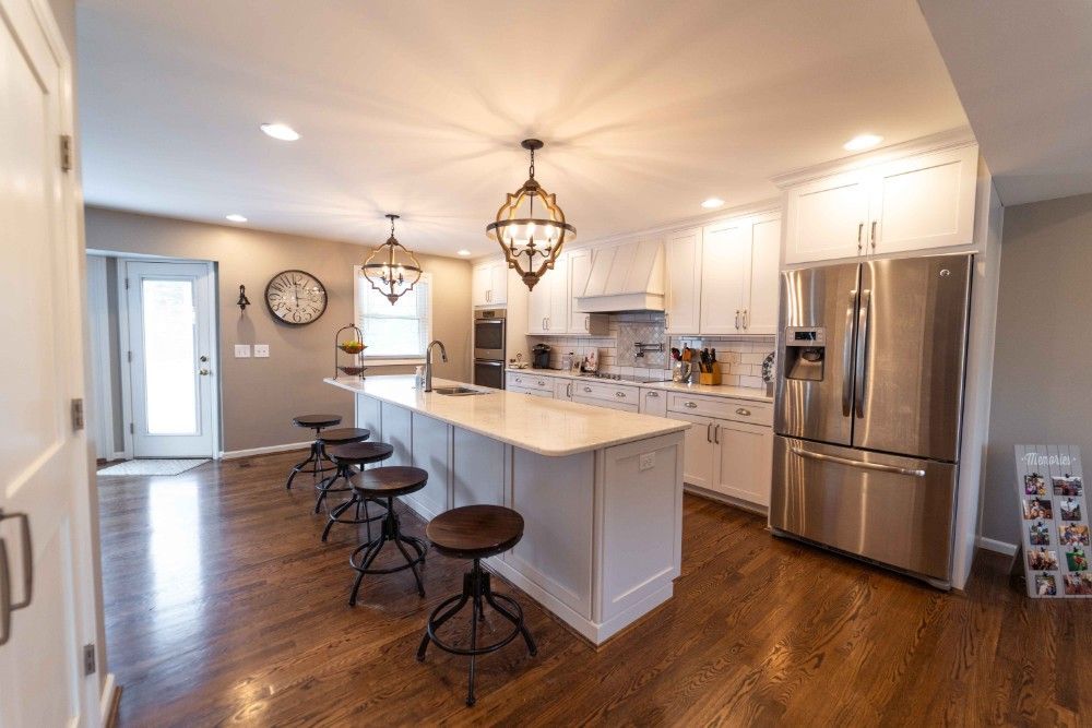 A kitchen with white cabinets and stainless steel appliances and a large island.