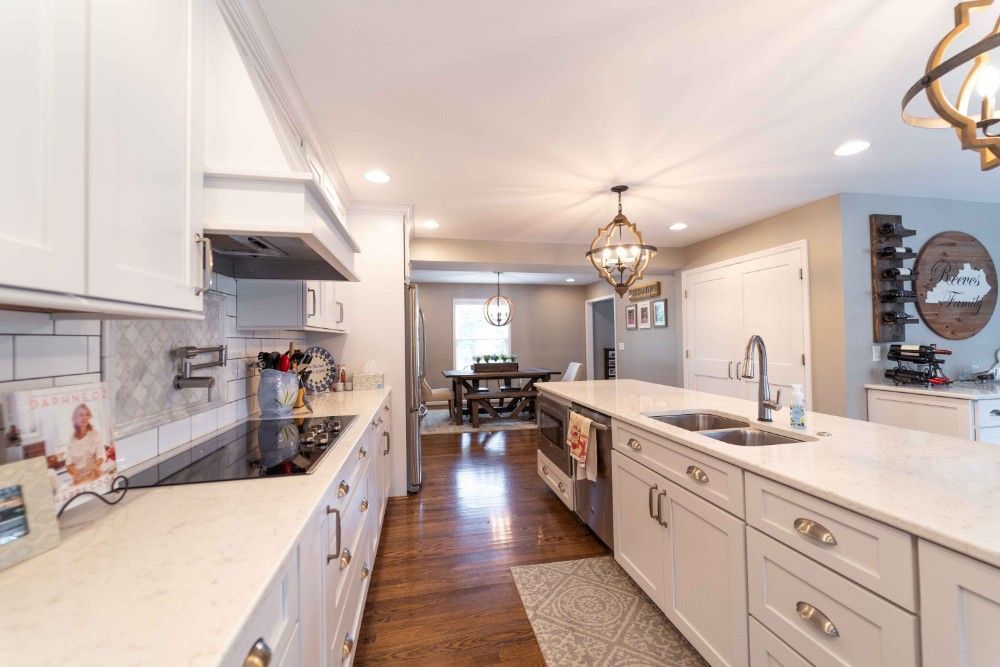 A kitchen with white cabinets , granite counter tops , stainless steel appliances and a large island.