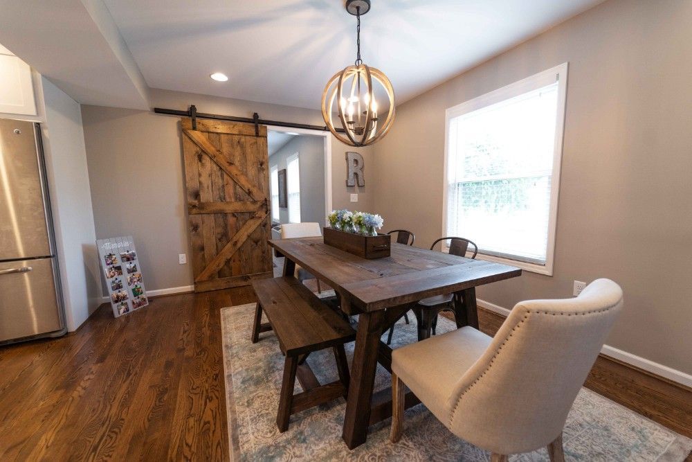 A dining room with a wooden table and chairs and a sliding barn door.