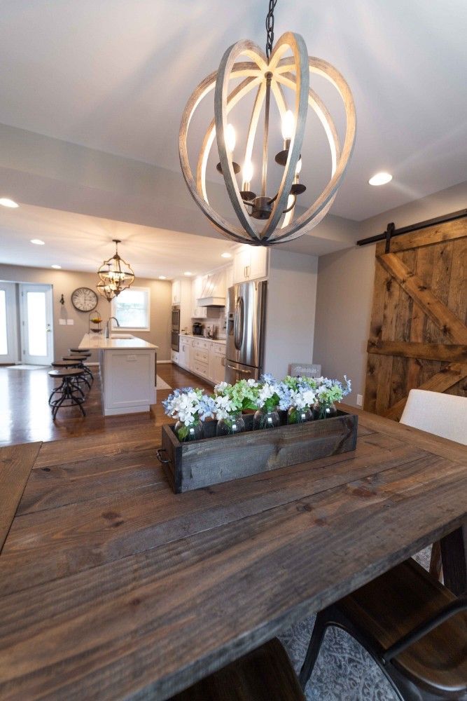 A wooden table with a vase of flowers on it in a dining room.