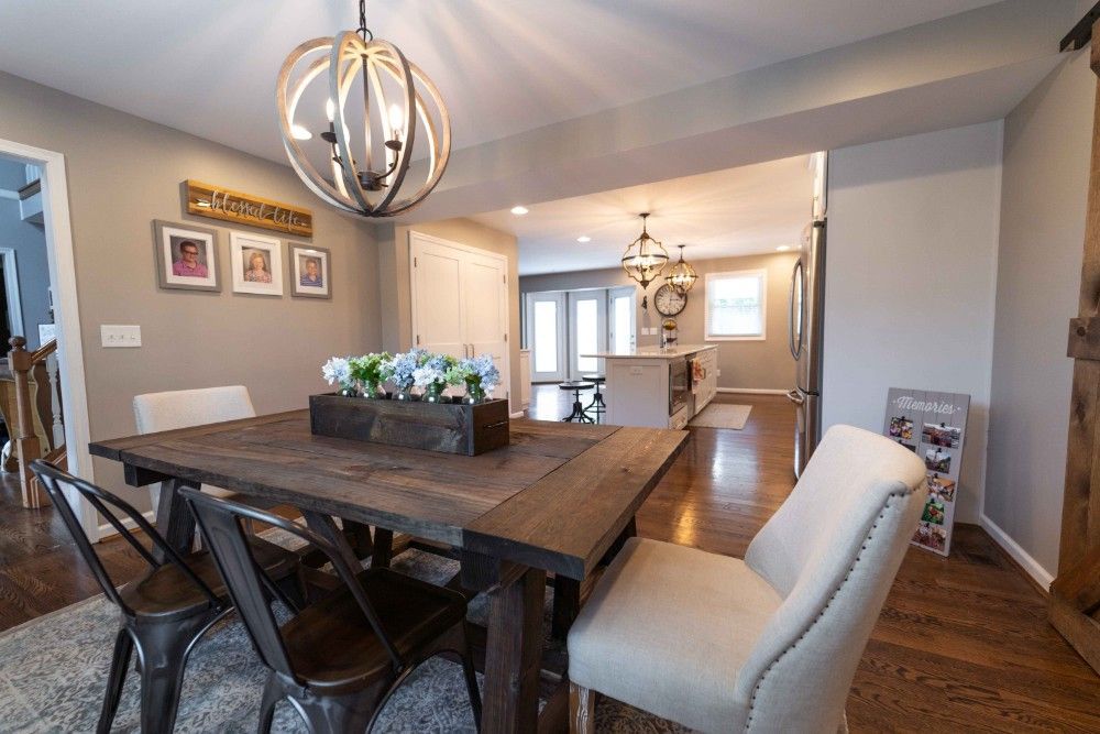 A dining room with a wooden table and chairs and a chandelier.