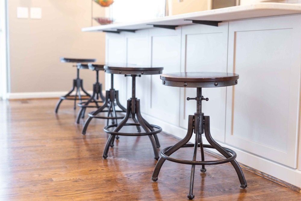 A row of bar stools sitting next to a counter in a kitchen.
