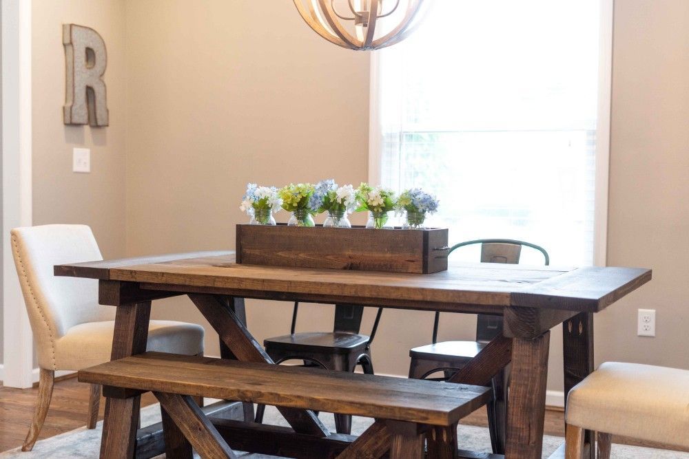 A wooden dining table with a bench and chairs in a dining room.