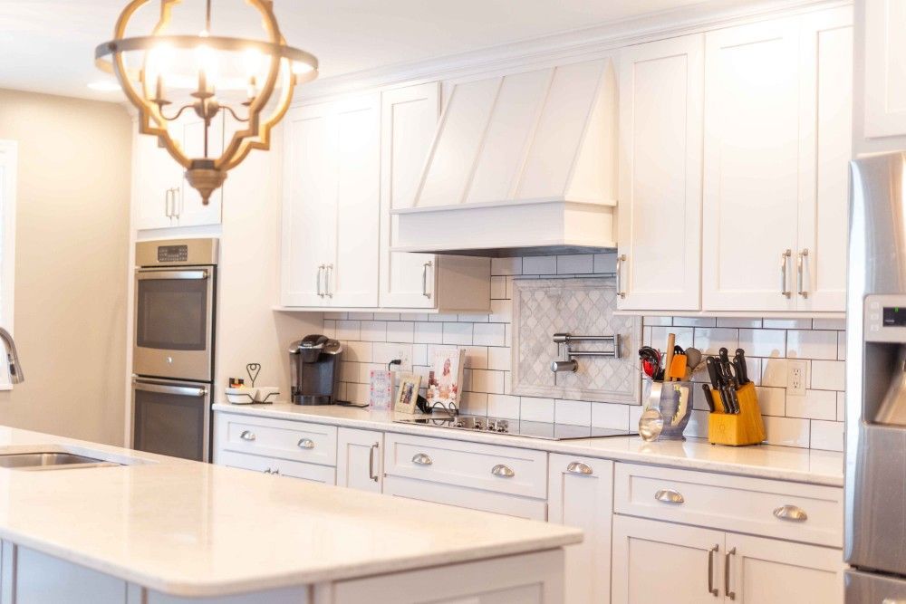 A kitchen with white cabinets , stainless steel appliances , and a large island.