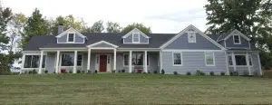A large house with a lot of windows is sitting on top of a lush green field.