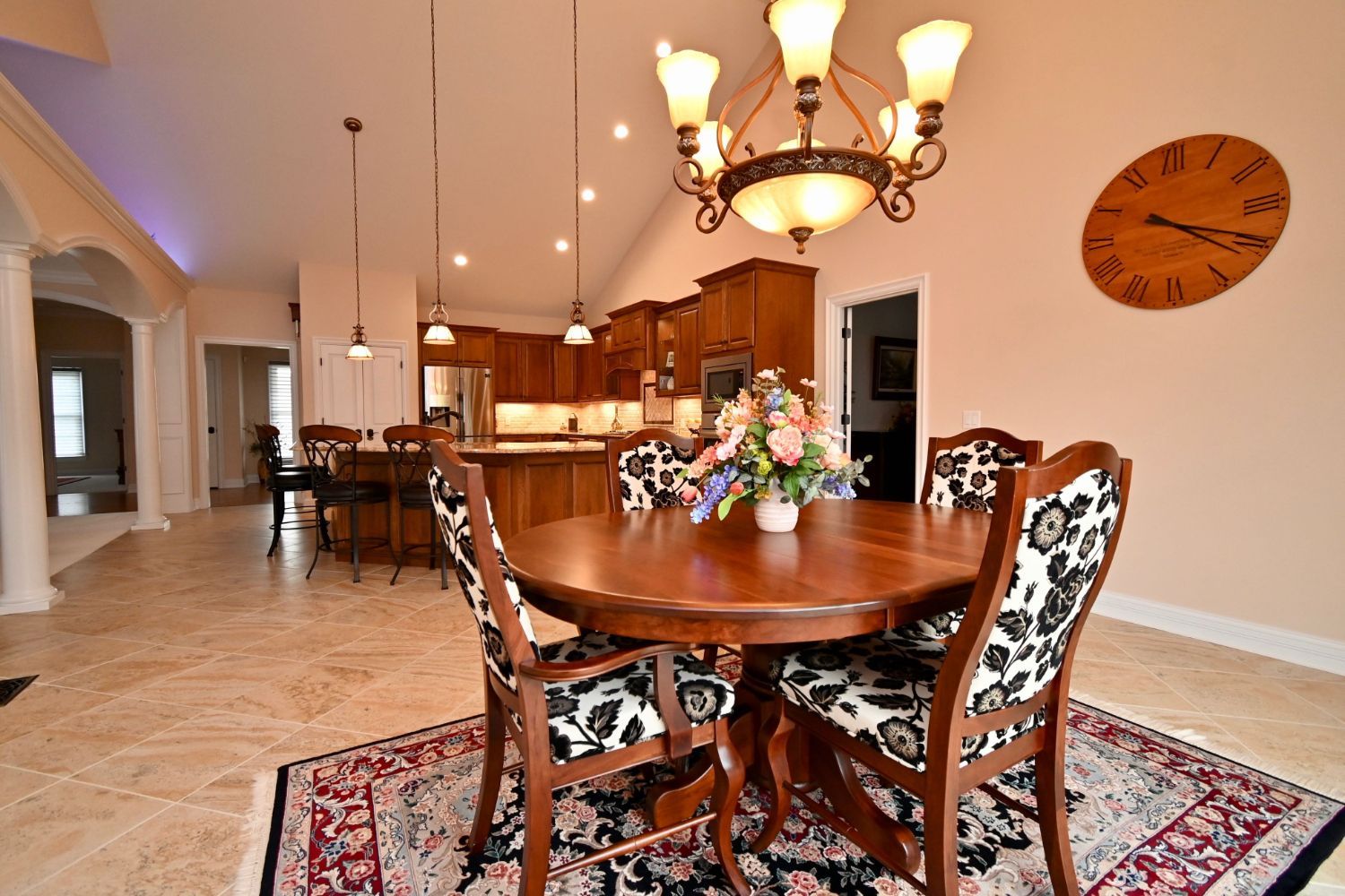 A dining room with a table and chairs and a clock on the wall
