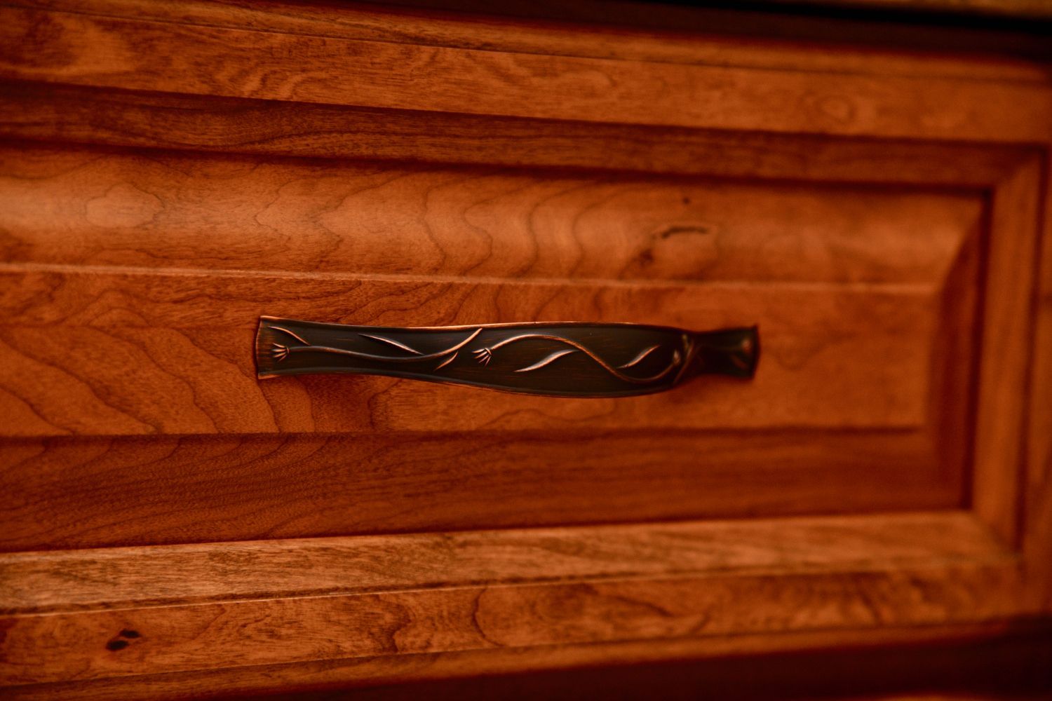A close up of a wooden drawer with a metal handle.