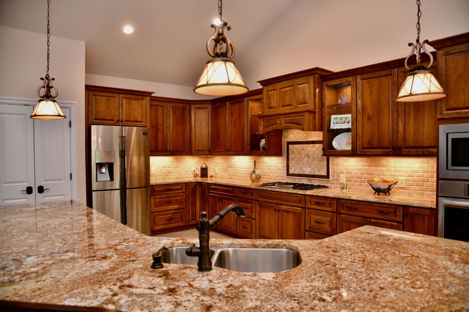 A kitchen with stainless steel appliances , granite counter tops , and wooden cabinets.