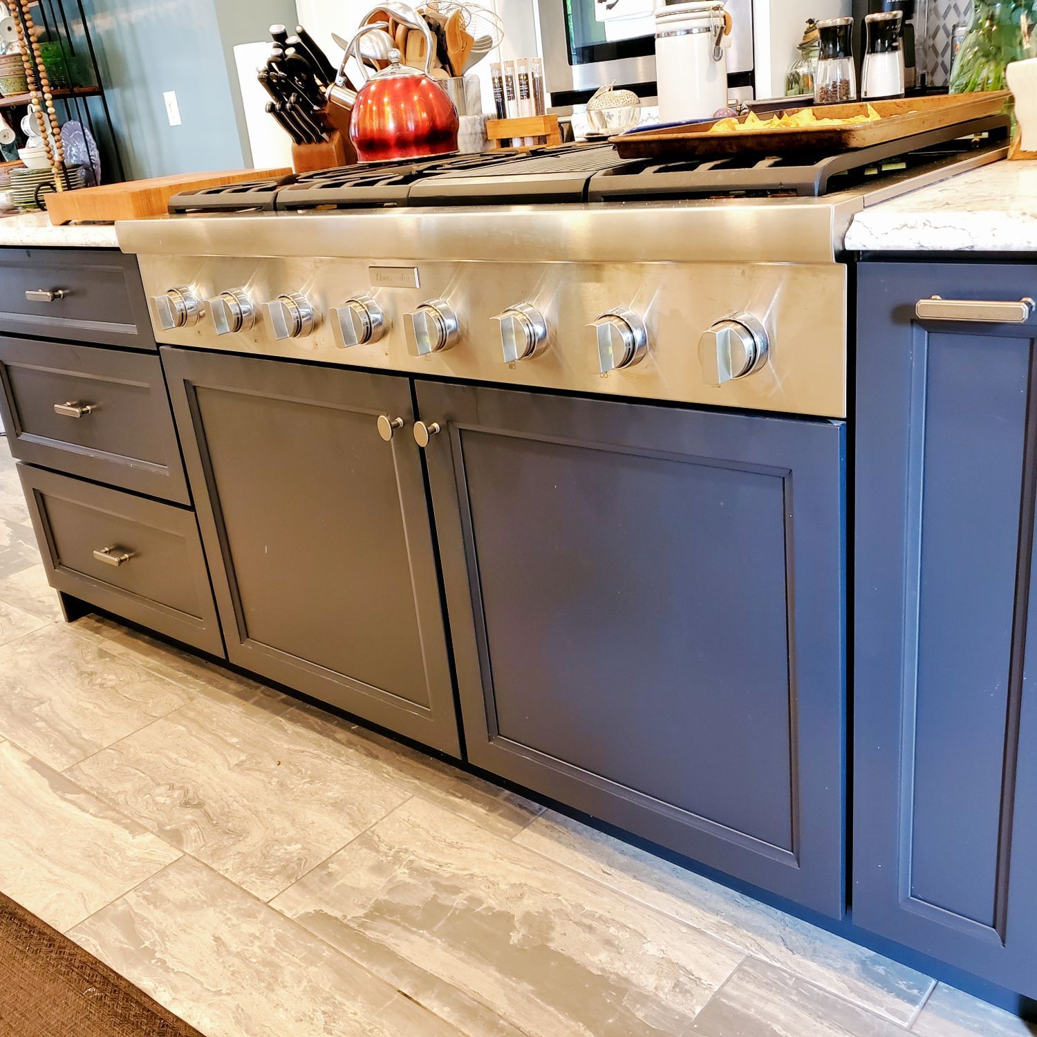 A kitchen with blue cabinets and a stove top oven.