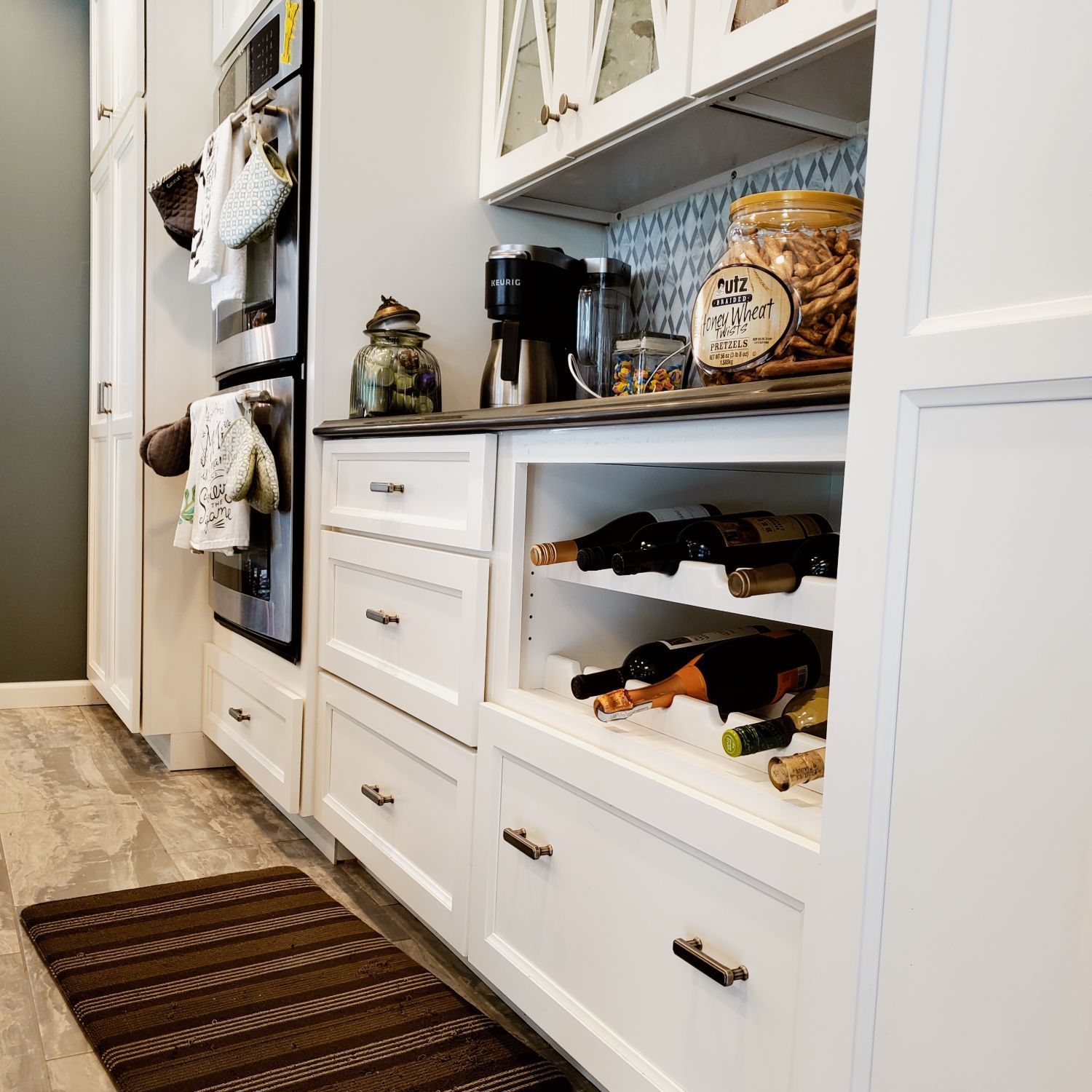 A kitchen with white cabinets and a wine rack