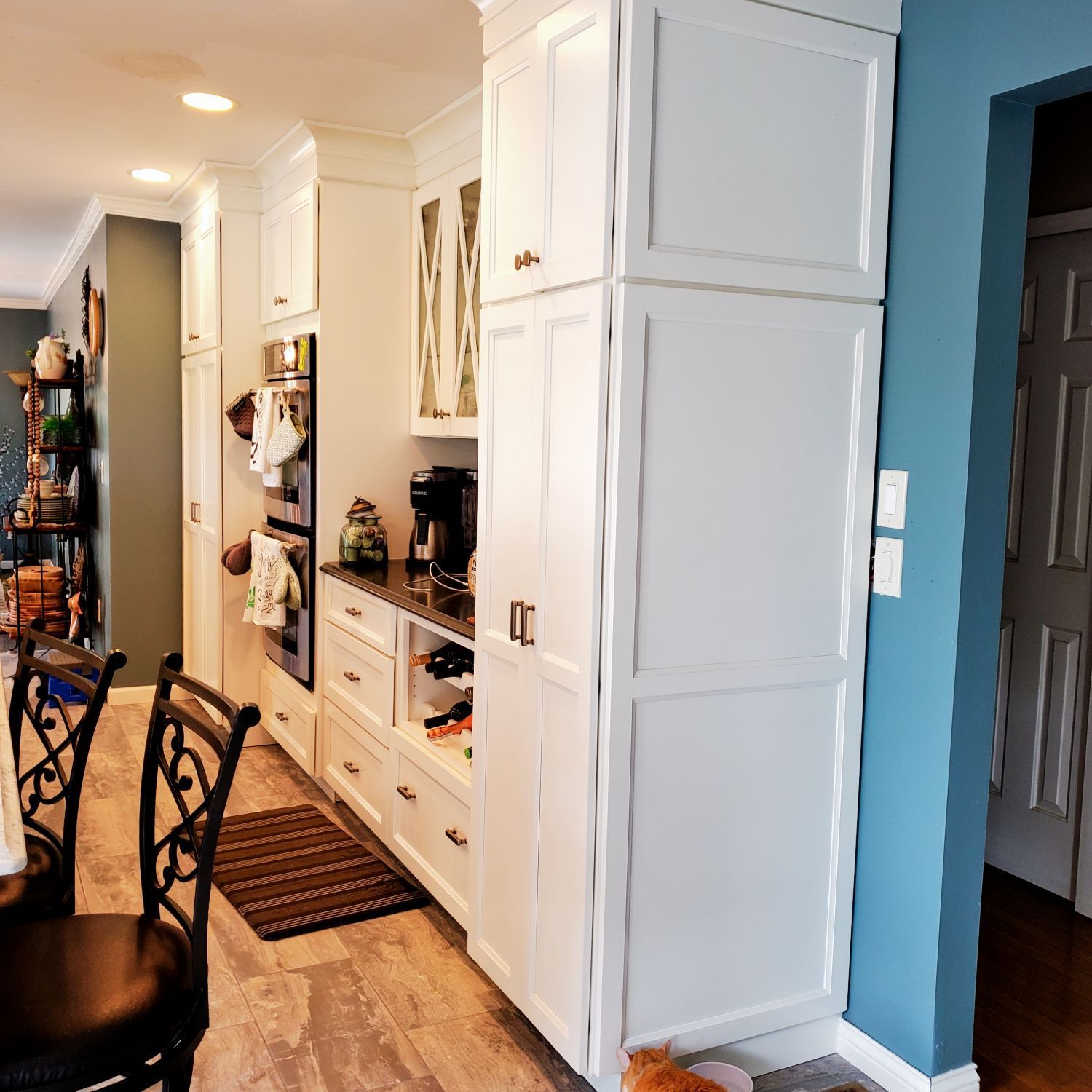 A kitchen with white cabinets and a blue wall