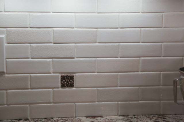 A close up of a white subway tile wall in a kitchen.