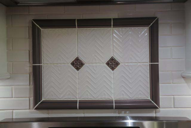 A picture frame is hanging on a wall above a stove.