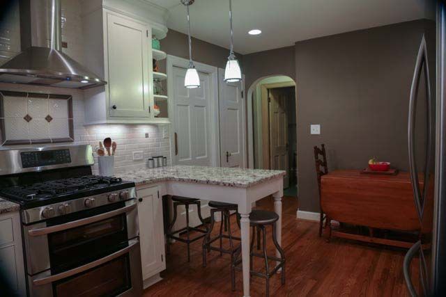 A kitchen with a stove , refrigerator , table and chairs.