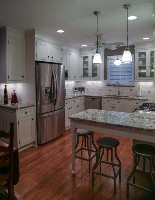 A kitchen with white cabinets and a stainless steel refrigerator