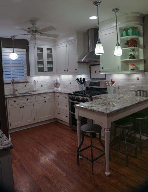A kitchen with white cabinets a stove and a table
