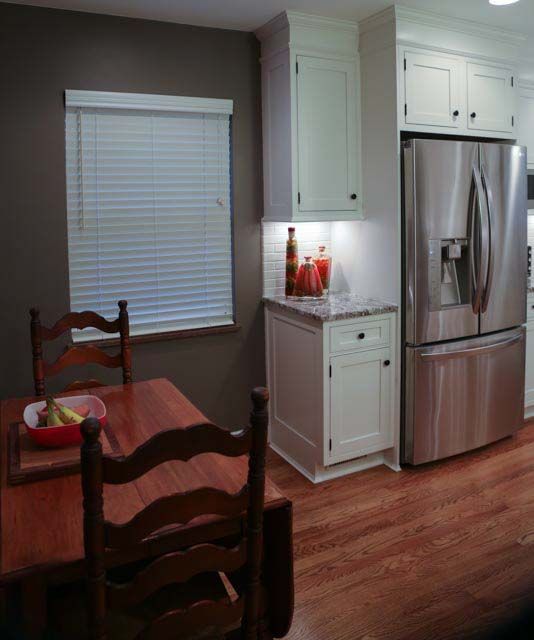 A kitchen with a table and chairs and a stainless steel refrigerator