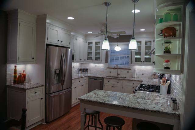 A kitchen with white cabinets , granite counter tops , stainless steel appliances and a large island.