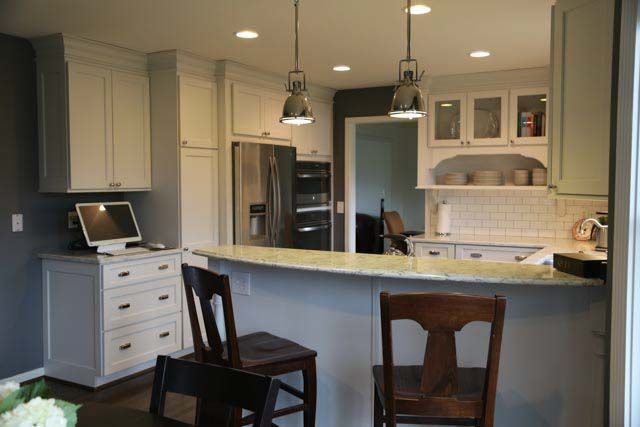 A kitchen with white cabinets and a marble counter top