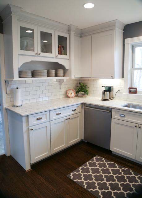 A kitchen with white cabinets , a dishwasher , a sink , and a rug.