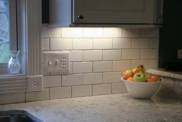 There is a bowl of fruit on the counter in the kitchen.