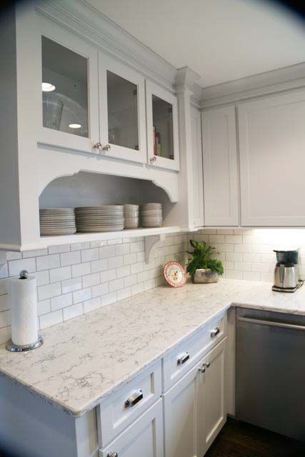 A kitchen with white cabinets , white counter tops , and a dishwasher.