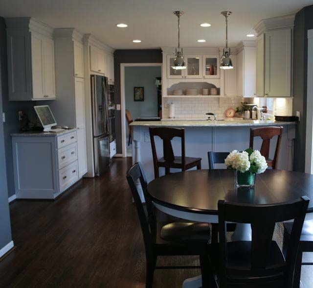 A kitchen with a table and chairs and a vase of flowers on the table
