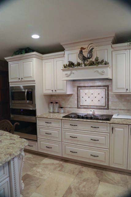 A kitchen with white cabinets and a rooster above the stove