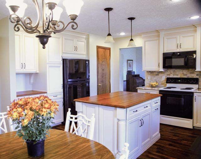 A kitchen with white cabinets and a large island in the middle