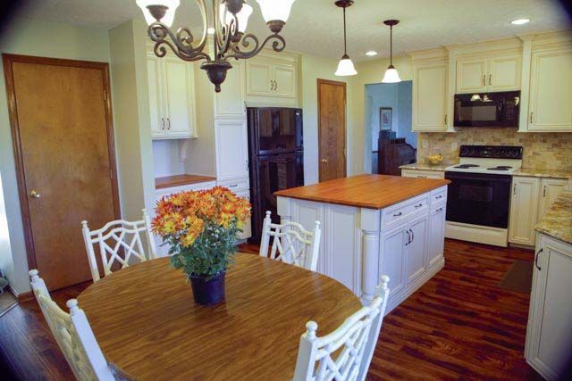 A kitchen with a table and chairs and a vase of flowers on the table