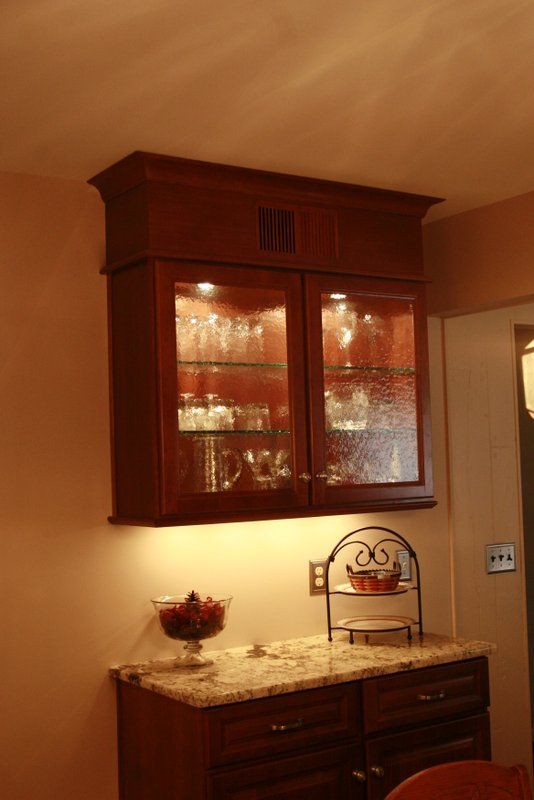 A cabinet with glass doors and a granite counter top in a kitchen.