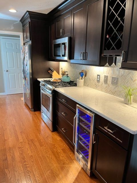 A kitchen with dark cabinets and a wine cooler