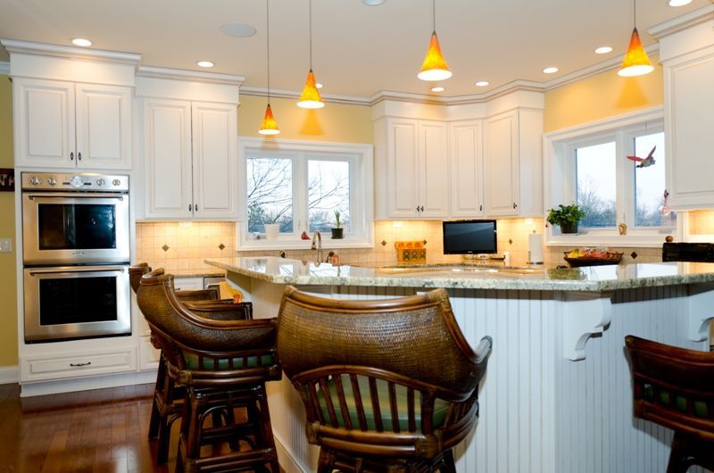 A kitchen with white cabinets and stools and a large island