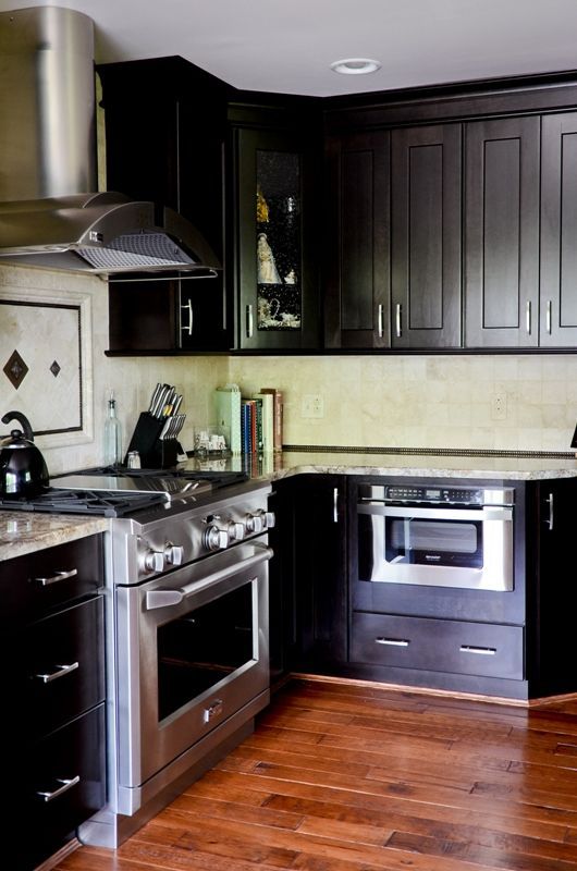 A kitchen with black cabinets and stainless steel appliances