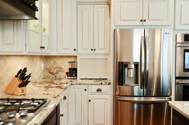 A kitchen with stainless steel appliances and white cabinets.