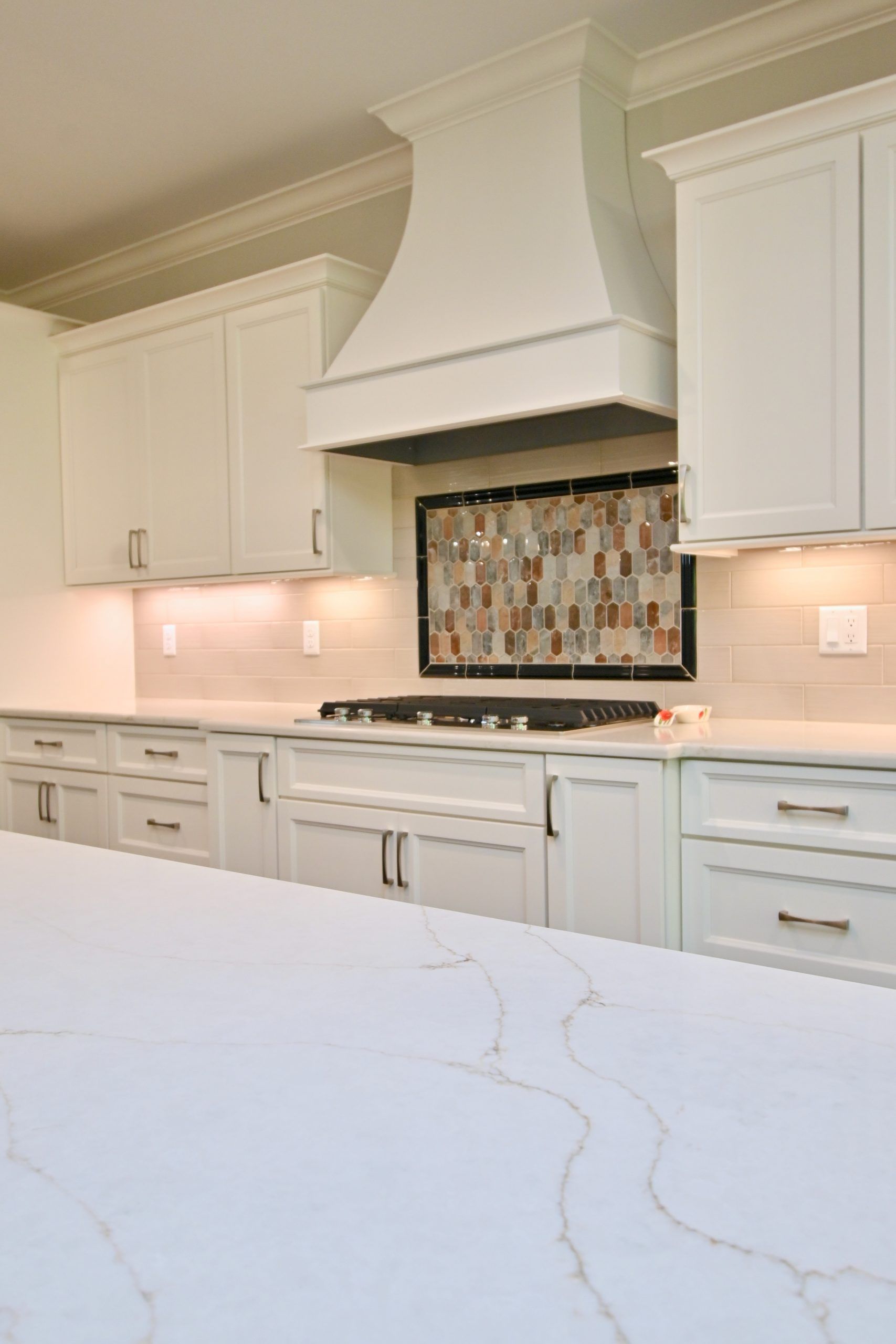 A kitchen with white cabinets , a stove , and a counter top.