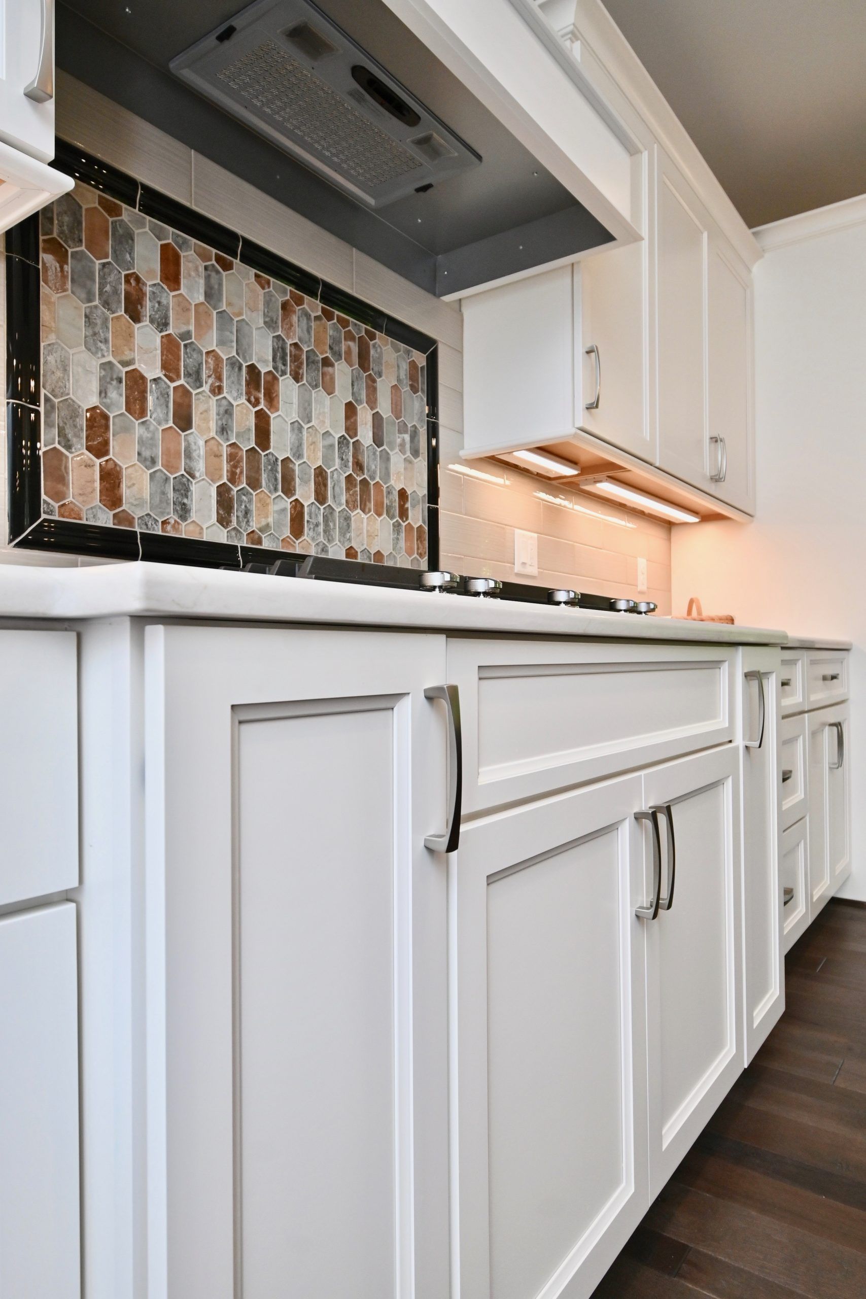 A kitchen with white cabinets and a stove top oven.
