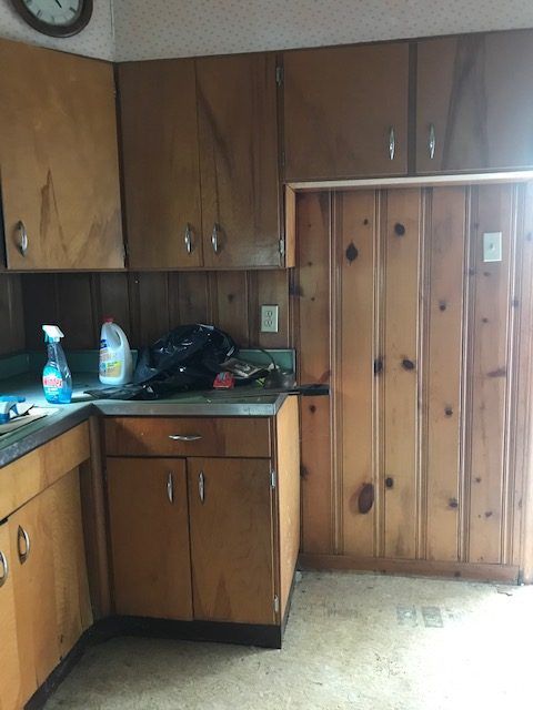 A kitchen with wooden cabinets and a clock on the wall