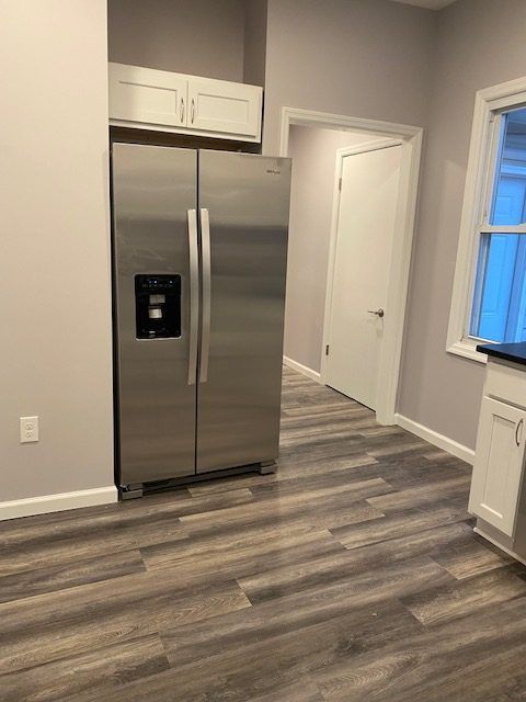 A stainless steel refrigerator is sitting in a kitchen next to a window.