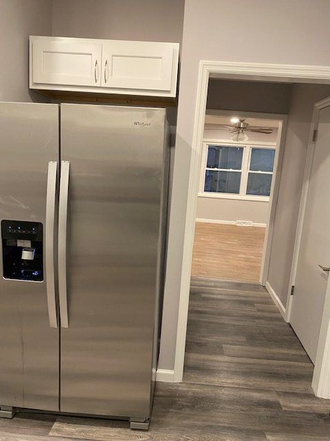 A stainless steel refrigerator is sitting in a kitchen next to a door.