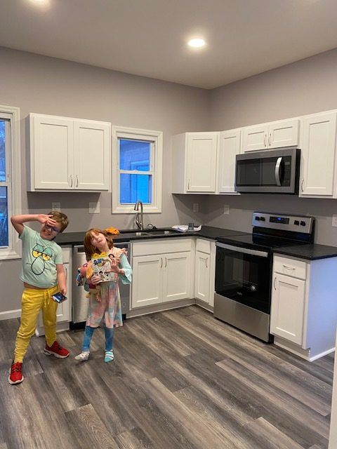 A boy and a girl are standing in a kitchen.