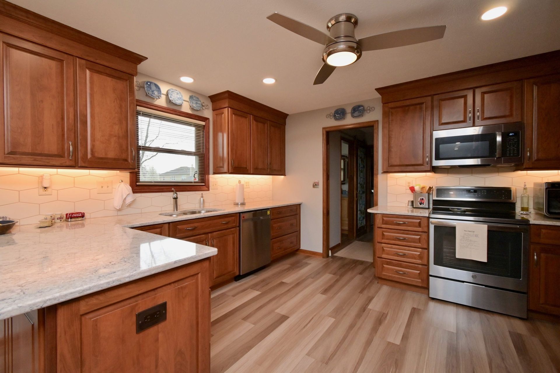 A kitchen with wooden cabinets , stainless steel appliances , and a ceiling fan.