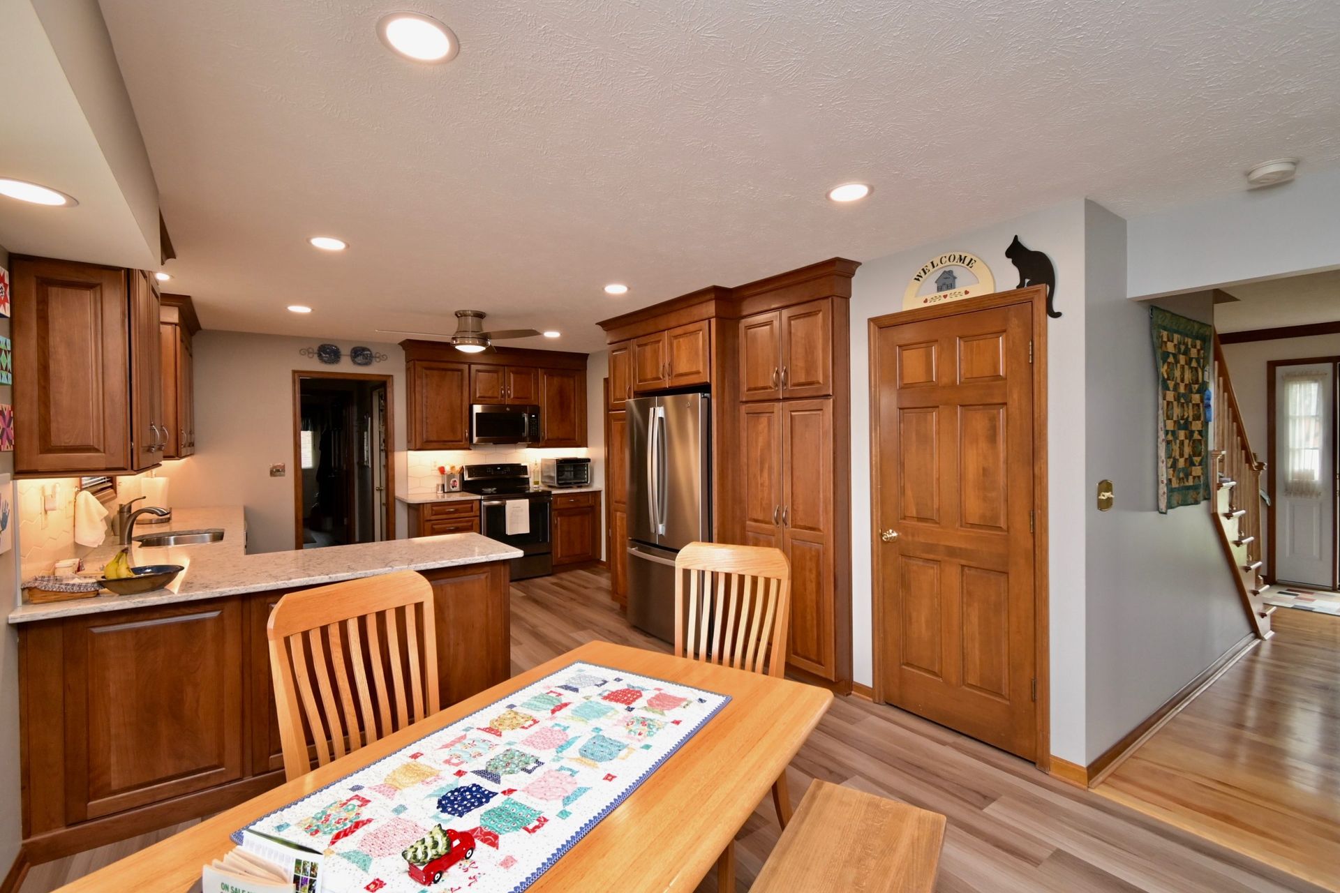 A kitchen with a table and chairs and a cat on the wall.