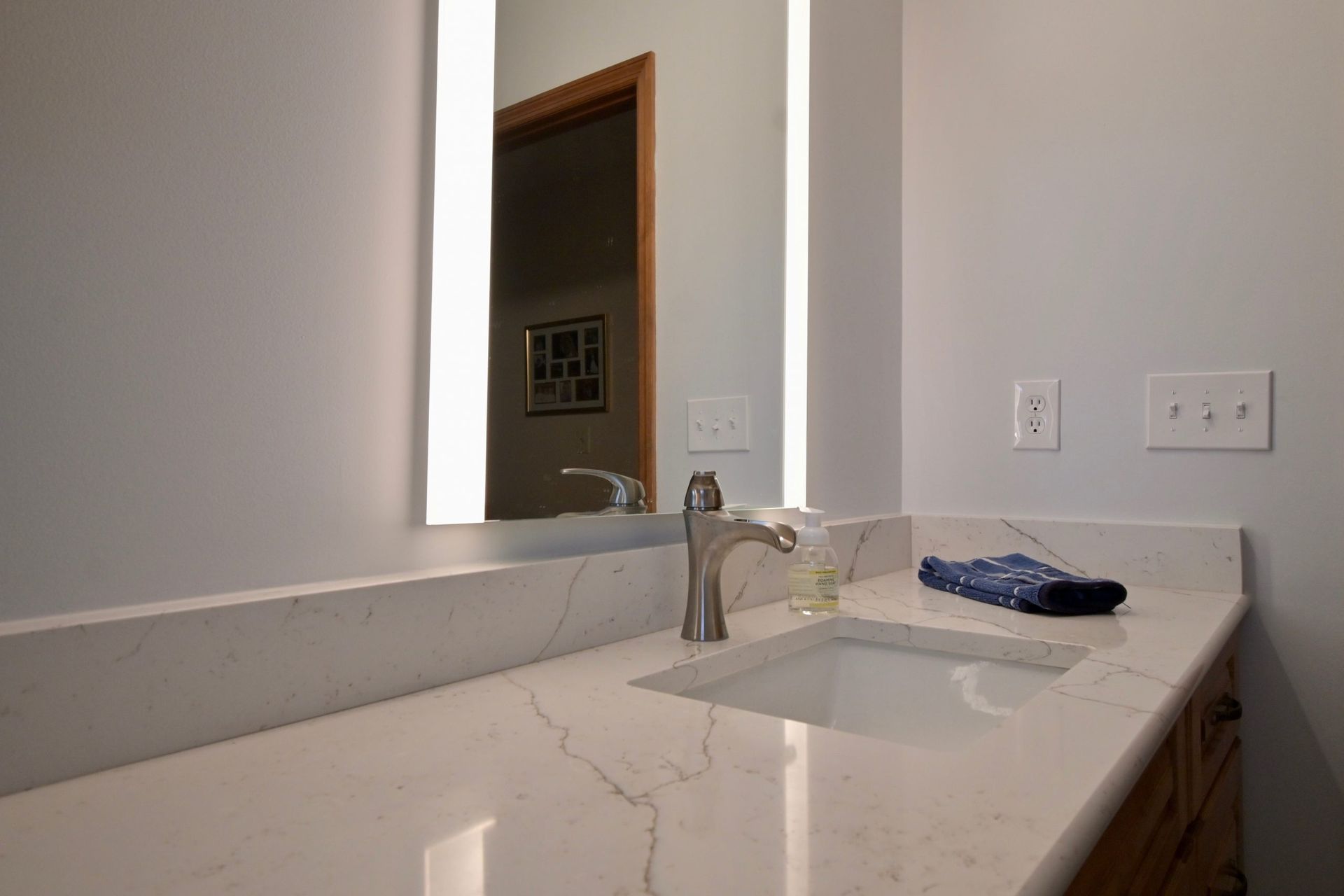 A bathroom with a sink , mirror and towel on the counter.