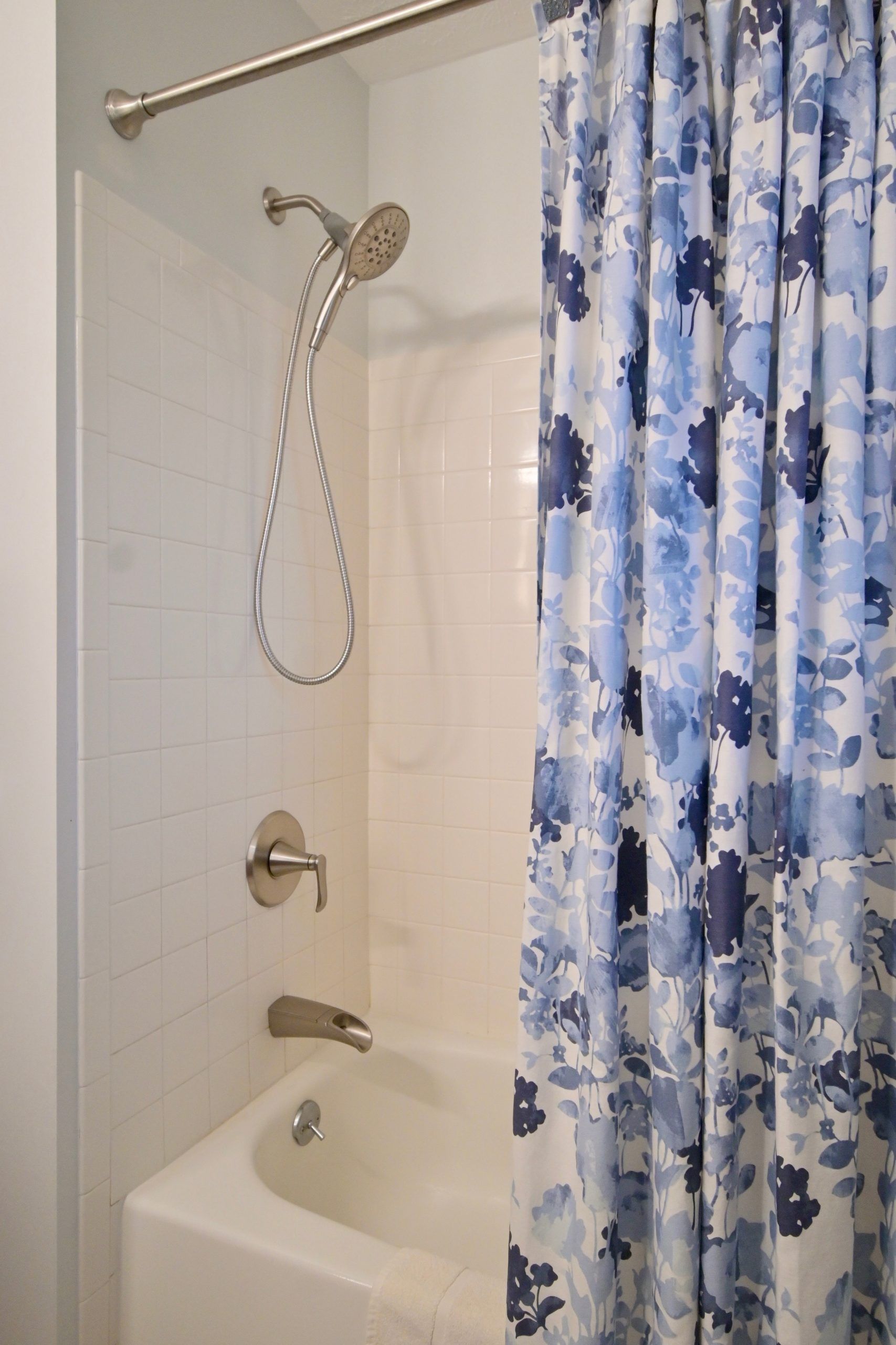 A bathroom with a blue shower curtain and a bathtub